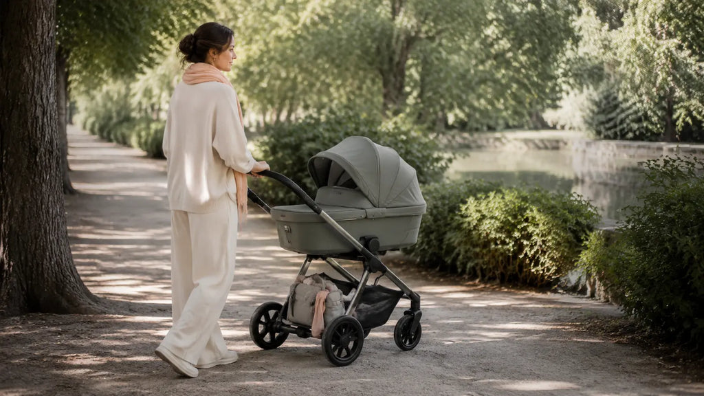 Parent promenant un nouveau-né en poussette dans un parc calme et lumineux