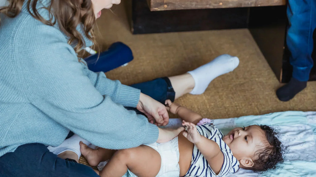 Mère prenant soin de son nouveau né pendant le change, contexte des soins du cordon ombilical