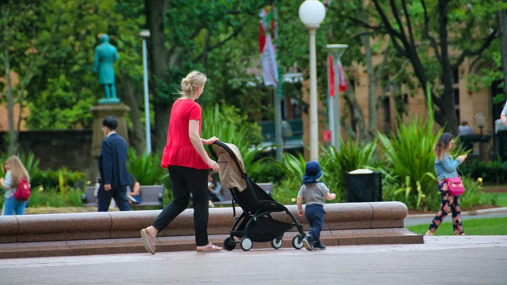 Parent en promenade avec une poussette dans un parc, illustrant la reprise progressive de l’activité après l’accouchement